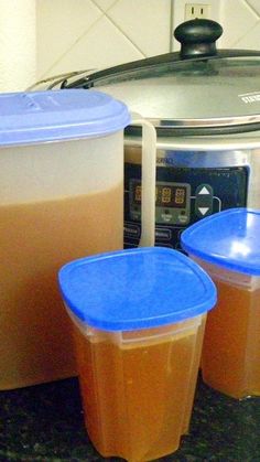 there are two containers with liquid in them next to an open crock pot on the stove