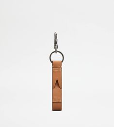 a brown leather keychain with an arrow on the front and back ends, hanging from a metal hook