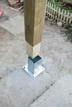 a metal pole with a wooden post sticking out of it's side on concrete