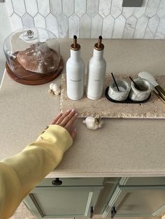 a person standing in front of a counter with two bottles on it and some garlic