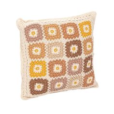 a crocheted pillow with yellow and brown flowers on the front, sitting on a white surface