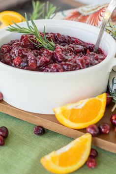 cranberry sauce in a white bowl garnished with rosemary and orange slices