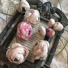 several pink flowers are placed on top of an old book with wire in the middle