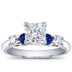 a diamond and blue sapphire engagement ring with three stones on the band, set in white gold