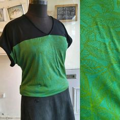 a green and black top sitting on top of a mannequin