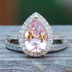 an engagement ring with a pear shaped pink diamond surrounded by white and clear diamonds on top