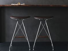 two stools sitting next to each other in front of a wooden table and shelf