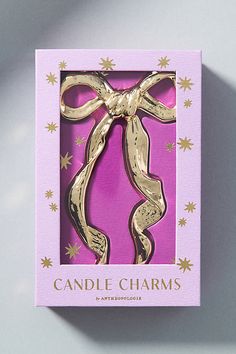 a pink and gold box with a bow on it that says candle charms in the middle