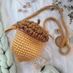 a crocheted bag sitting on top of a bed next to a cup and saucer