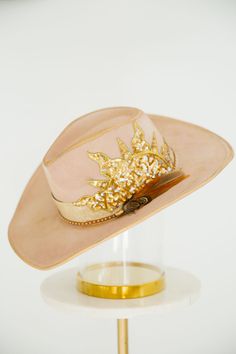 SUNLIGHT SEQUIN RANCHER is a classic rancher hat with a unique twist. It features a sequin sun patch, a stylish snakeskin band, and stunning gold glitter accents. This one of a kind hat adds a touch of glamour to your outfit. This hat is ONE OF A KIND, created by our owner Stephanie. To receive item quicker, expedited shipping is available at checkout. Gold Flat Brim Hat Bands For Kentucky Derby, Gold Flat Brim Hat For Rodeo, Gold Western Hat Band For Kentucky Derby, Western Gold Hat Bands For Kentucky Derby, Western Gold Hat Bands For Party, Western Style Gold Hat Bands For Parties, Western Gold Hat Band For Rodeo, Gold Western Hat Band For Western-themed Events, Gold Western-style Hat Band For Western-themed Events