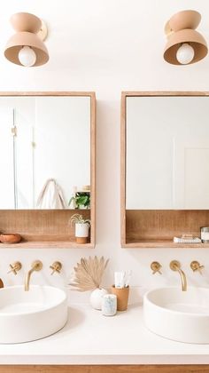 two bathroom sinks with mirrors above them in front of a wall mounted mirror and light fixture