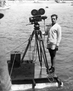 a man standing next to a camera on top of a boat