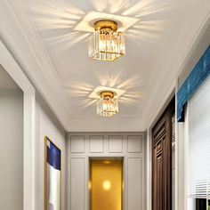 a hallway with white walls and blue carpeted flooring next to a doorway that has two lights on each side of the door