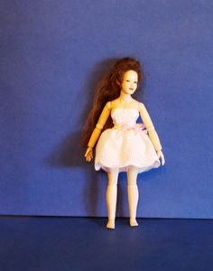 the doll is wearing a white dress and pink shoes