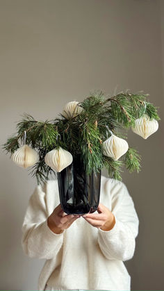 a woman holding a plant with white ornaments on it