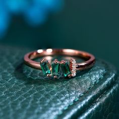 an emerald colored ring sitting on top of a green surface