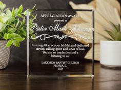 a glass award sitting on top of a table next to a potted plant