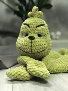 a crocheted stuffed animal laying on top of a wooden floor next to a plant