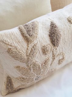 a close up of a pillow on a bed with white sheets and pillows behind it