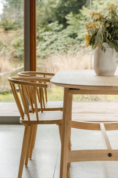 a wooden table with two chairs next to it and a potted plant on the table