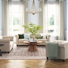 a living room filled with furniture and a chandelier hanging from the ceiling over a wooden coffee table