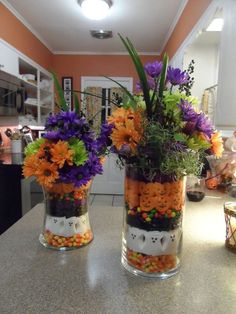 two glass vases filled with candy and flowers on top of a kitchen countertop