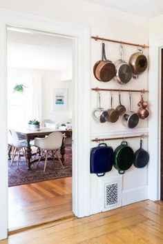 pots and pans are hanging on the wall in this dining room with hardwood floors