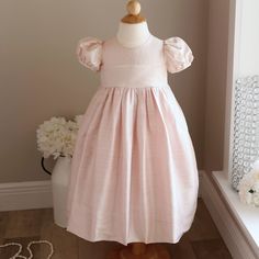 This Little Girl's Silk Dress Is Gorgeous!! The 100% Dupioni Silk Dress Is Done In A Beautiful Blush Pink Hue. A Rounded Neckline Keeps The Dress Simple And Elegant. A Wide Ivory Silk Organdy Sash Ties Into A Big Billowy Bow In Back-Just Beautiful!! The Short Puff Sleeves Gather At The Shoulder And Hem Which Has A Matching Piping. The Back Has A Yoke With An Upper Button Back Closure Done In Lovely Full Ivory Pearlized Shank Buttons. The Skirt Has A Sew-0n Liner And Also A Slip Liner Which Has A Dupioni Silk Dress, Girl Silk Dress, Dupioni Silk, Dress Simple, Ivory Silk, Dress Silk, Shank Button, Silk Organza, Rounded Neckline