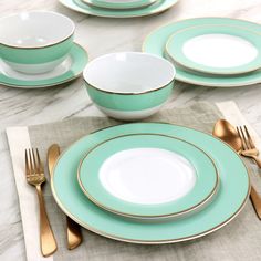 a table set with plates, silverware and gold rimmed utensils on it