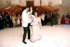 a bride and groom dancing on the dance floor in front of their guests at a wedding