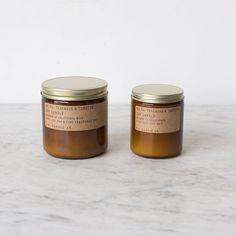 two jars with labels on them sitting on a marble countertop next to each other