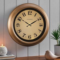 a clock that is on the wall next to a potted plant and a candle