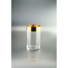 an empty glass with a gold rim sitting on a white table next to a gray wall