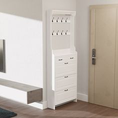 a tall white cabinet sitting in the corner of a living room next to a door