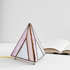 an open book sitting on top of a white table next to a stained glass lamp