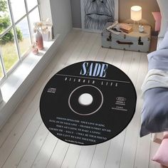 a bedroom with a bed, window and white flooring has a black vinyl record on the floor