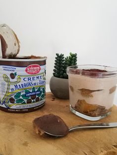 a jar of ice cream sitting on top of a wooden table next to a spoon