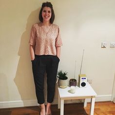 a woman standing next to a white table with a plant on it and a radio in the background