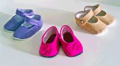 three pairs of baby shoes sitting on top of a white table next to each other