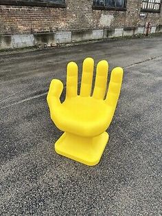 a yellow plastic hand sitting in the middle of a street