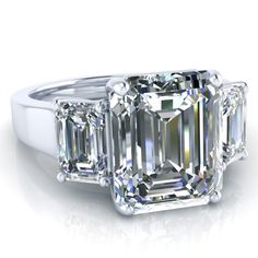 an emerald cut diamond ring with three baguets on the sides and four diamonds in the middle