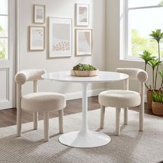 a white table and chairs in a room with pictures on the wall behind it,