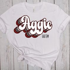 Get ready to show off your Aggie pride with this Aggie Gig 'em Shirt! Made with premium quality materials, this Texas A&M University t-shirt is perfect for any Aggie fan. Whether you're a current student, alumni, or just a proud supporter, this shirt is a must-have addition to your Aggie spirit apparel collection. Featuring the iconic Gig 'em slogan, this shirt showcases your love for Texas A&M in a stylish and trendy way. The comfortable and breathable fabric ensures a perfect fit and all-day comfort, making it suitable for everyday wear or game day excitement. This Aggie Gig 'em shirt is not only fashionable but also a great conversation starter. It makes a fantastic gift for Aggie friends, family, or anyone who wants to join in on the Aggie spirit. Wear it to football games, tailgates, School Spirit Shirt With Graphic Print, College T-shirt With Sublimation Print And Relaxed Fit, College Graphic Tee Shirt With Sublimation Print, School Spirit Graphic Print Relaxed Shirt, School Spirit Graphic Print Relaxed Fit Shirt, Retro Cotton T-shirt With Name Print, Relaxed Fit Sublimation Print Top For College, Team Spirit Relaxed Fit Top With Logo Print, College Cotton Shirt With Sublimation Print