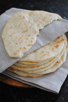 a stack of tortillas sitting on top of a wooden cutting board