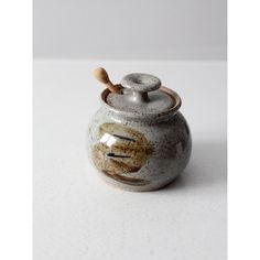 a small ceramic jar with a wooden handle