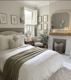 a bedroom with white bedding and pictures on the wall above the headboard, along with a fireplace