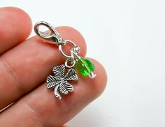 a hand holding a green charm with four leaf clover charms on it's side