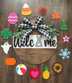 a welcome sign surrounded by decorations and magnets on a wooden table with a black and white bow