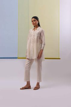 Beige and off white three fourth sleeves pleated yoke tunic with bloom gara thread embroidery. Paired with a pant. - Aza Fashions Elegant Long Sleeve Sets With Pintucks, Spring Long Sleeve Kurta With Pintucks, Spring Long Sleeve Pintuck Kurta, Off White Long Sleeve Sets For Spring, Spring Kurta With Floral Embroidery And 3/4 Sleeves, Spring Cotton Kurta With Pintucks, Summer Workwear Kurta With Long Sleeves, Long Sleeve Chikankari Kurta For Work, Long Sleeve Kurta With Floral Embroidery For Work