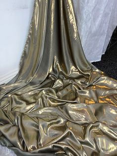 an image of a shiny gold cloth on the floor in front of a white wall